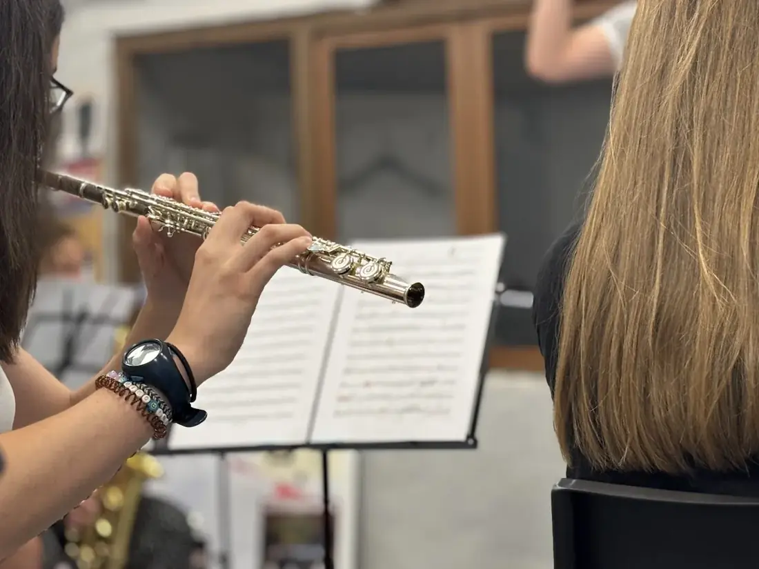 Detalle de una flautista de la Banda tocando junto a su partitura durante un ensayo